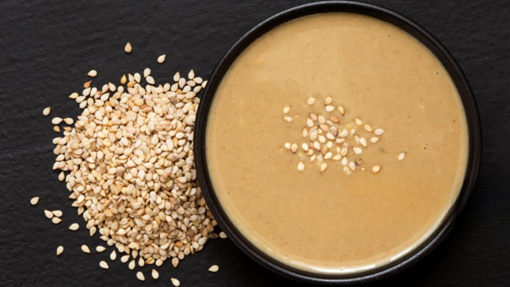 Tahini in a black bowl with sesame seeds on top