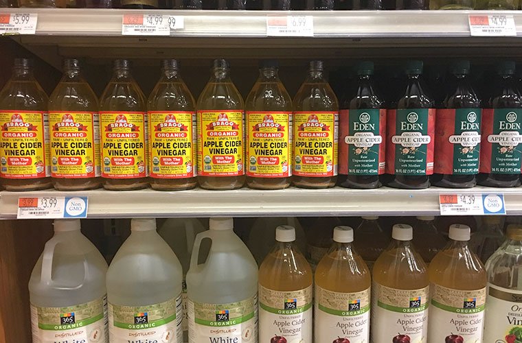 White and apple cider vinegar in glass bottles and plastic gallons on shelves